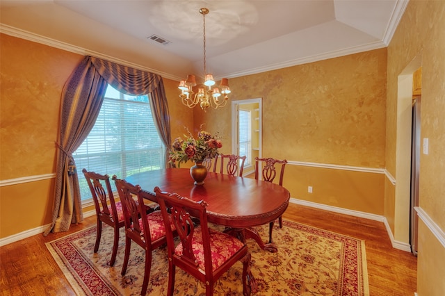 dining room with crown molding, a tray ceiling, a chandelier, and hardwood / wood-style flooring