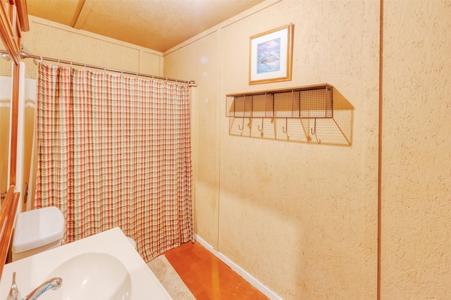 bathroom featuring curtained shower, toilet, and sink