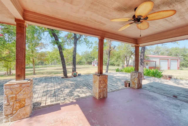 view of patio featuring ceiling fan, an outdoor structure, a garage, and a wooden deck