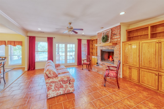 living room featuring ceiling fan, built in features, light tile patterned floors, a fireplace, and crown molding