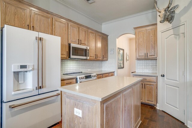 kitchen featuring backsplash, crown molding, stainless steel appliances, dark wood-type flooring, and a kitchen island