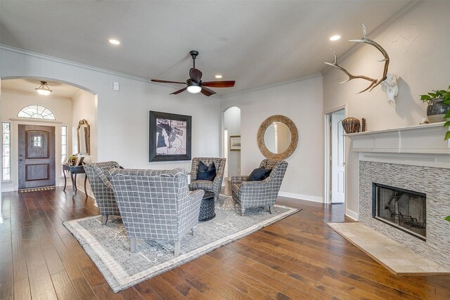 living room featuring ceiling fan, a tile fireplace, dark hardwood / wood-style floors, and ornamental molding