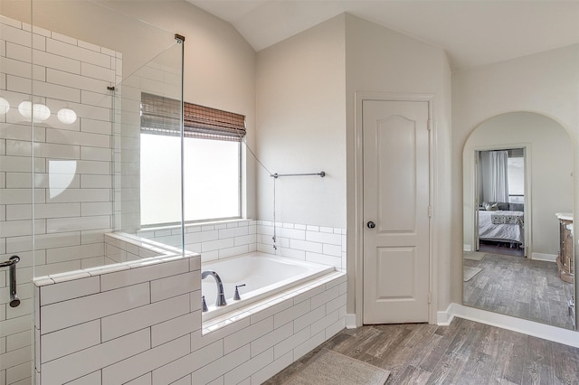 bathroom featuring shower with separate bathtub, vaulted ceiling, and hardwood / wood-style floors