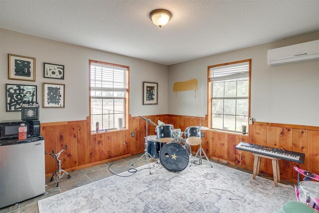 misc room with wooden walls, a wall unit AC, plenty of natural light, and a textured ceiling