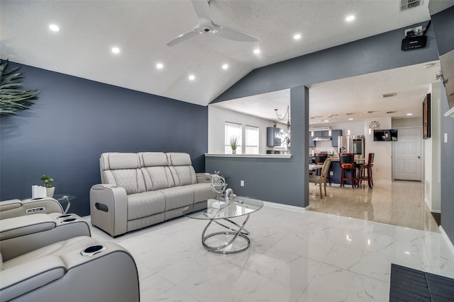 living room featuring lofted ceiling, ceiling fan with notable chandelier, and a textured ceiling