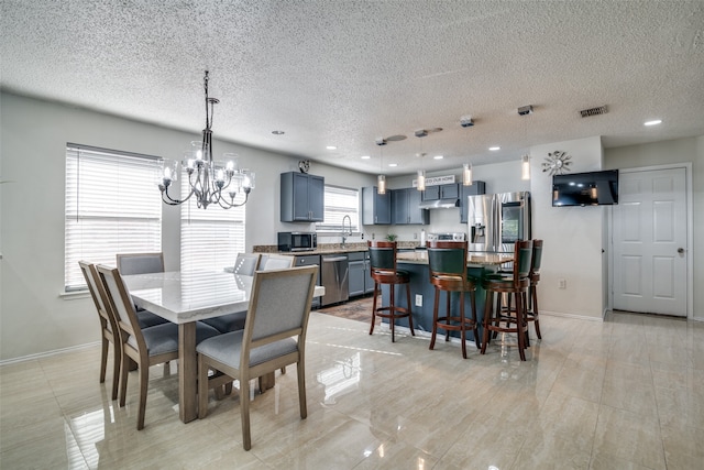 dining space with a textured ceiling, a notable chandelier, and sink