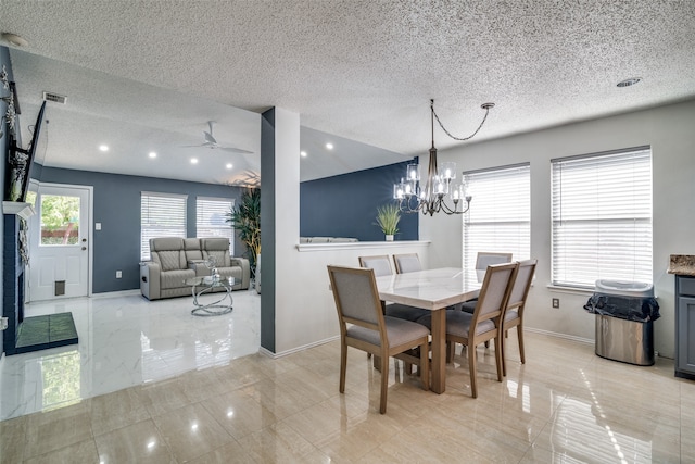 dining space featuring a textured ceiling, ceiling fan with notable chandelier, and a fireplace