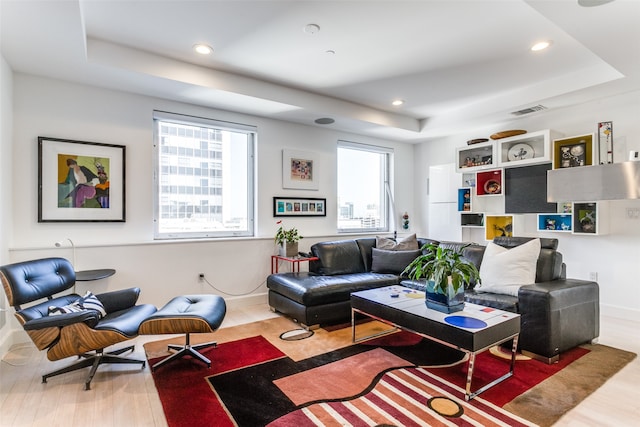 living room with hardwood / wood-style floors and a raised ceiling