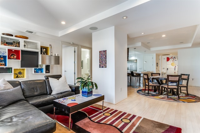 living room featuring a tray ceiling and light hardwood / wood-style floors