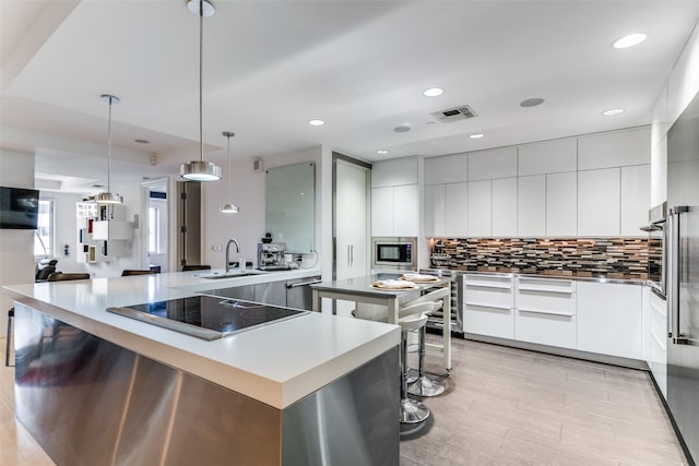 kitchen with a kitchen island, pendant lighting, backsplash, stainless steel appliances, and sink