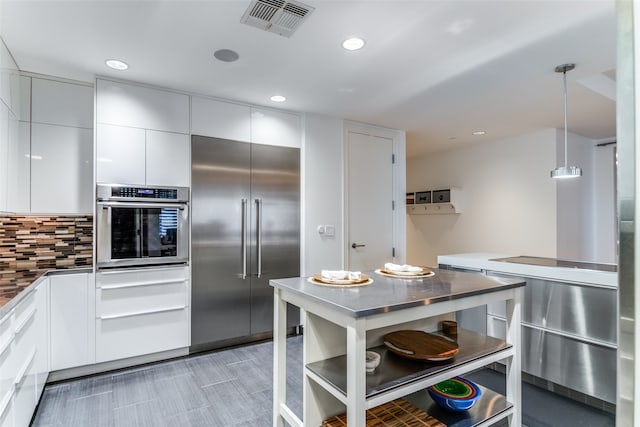 kitchen with decorative light fixtures, stainless steel appliances, tasteful backsplash, and white cabinetry