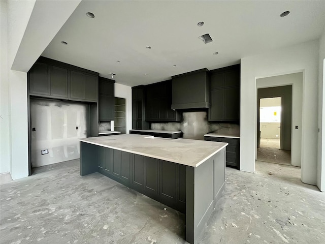 kitchen featuring a large island, light stone countertops, backsplash, and custom exhaust hood