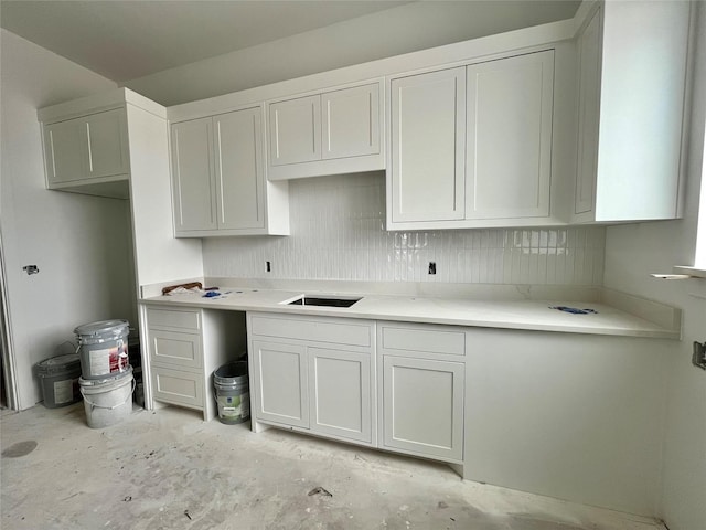 kitchen with backsplash, white cabinetry, and sink