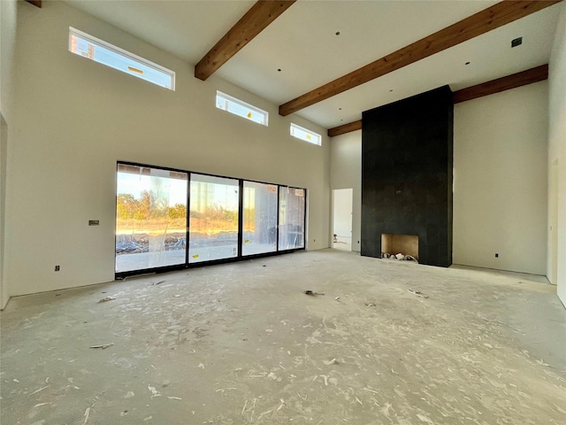 unfurnished living room with beamed ceiling, a towering ceiling, and a wealth of natural light