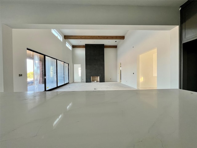 unfurnished living room featuring a fireplace and beamed ceiling