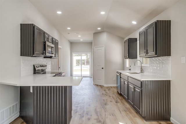 kitchen featuring light hardwood / wood-style floors, sink, kitchen peninsula, a kitchen bar, and stainless steel appliances