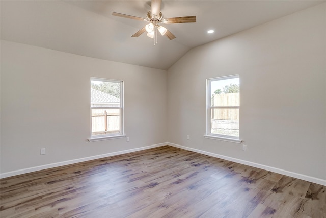 empty room featuring light wood-type flooring, lofted ceiling, ceiling fan, and plenty of natural light