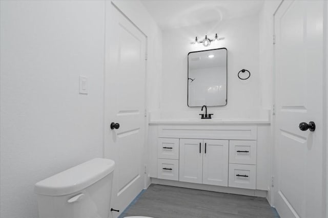 bathroom with hardwood / wood-style flooring, vanity, and toilet