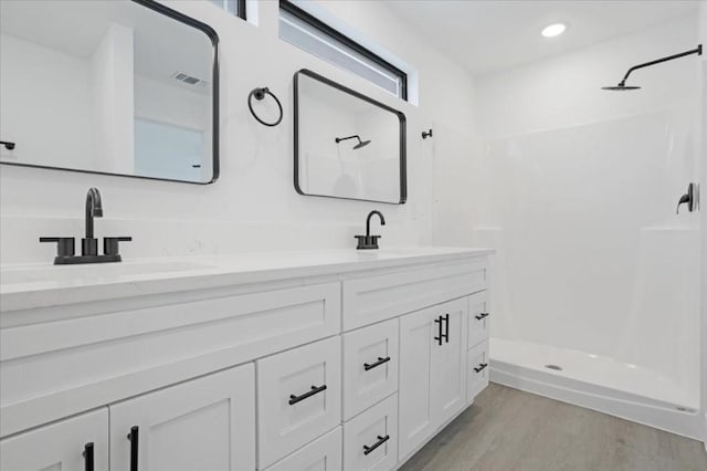 bathroom featuring hardwood / wood-style floors, vanity, a shower, and a wealth of natural light