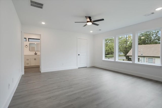 unfurnished bedroom featuring ceiling fan, wood-type flooring, and ensuite bath