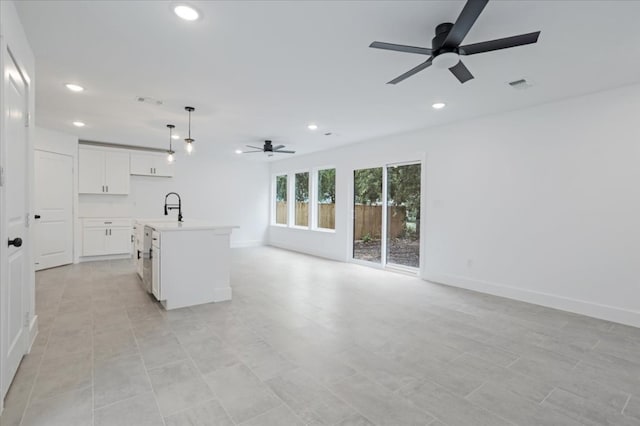 kitchen with a kitchen island with sink, white cabinets, sink, hanging light fixtures, and ceiling fan