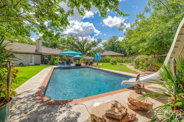 view of swimming pool featuring a yard, a water slide, and a patio