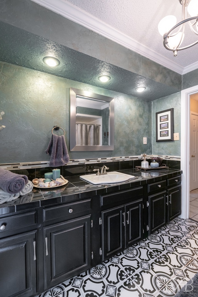 bathroom with ornamental molding, vanity, and a textured ceiling