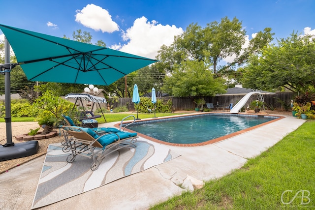 view of pool featuring a lawn, a water slide, and a patio area