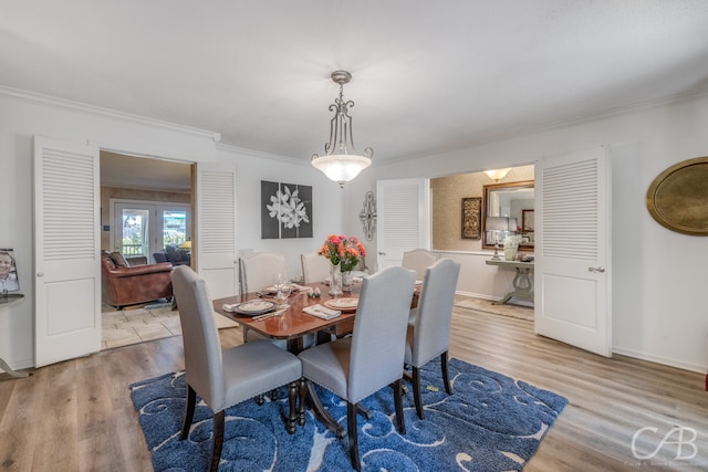 dining room with crown molding and light hardwood / wood-style flooring