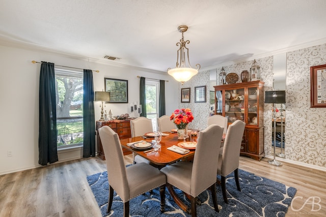 dining area with crown molding, plenty of natural light, and light hardwood / wood-style flooring