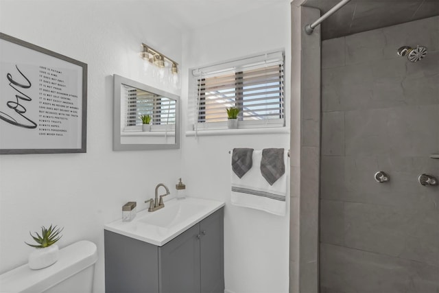 bathroom with toilet, vanity, and tiled shower