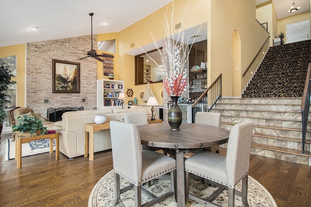 dining room featuring high vaulted ceiling, a brick fireplace, ceiling fan, and dark hardwood / wood-style floors