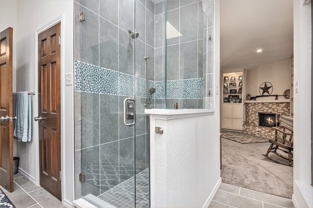 bathroom featuring a brick fireplace, tile patterned flooring, and an enclosed shower