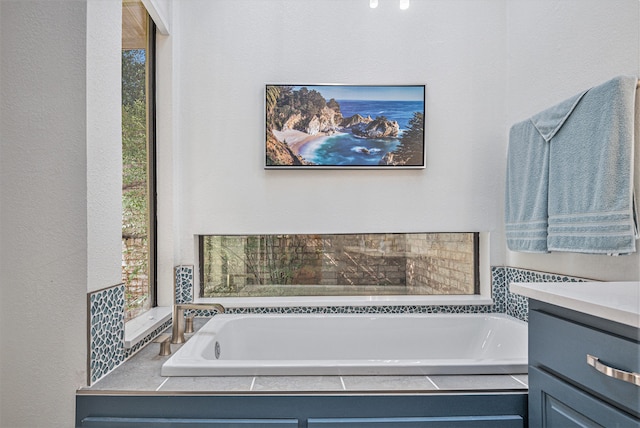 bathroom featuring a relaxing tiled tub and vanity