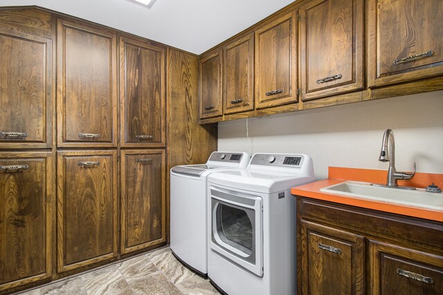 washroom with cabinets, washing machine and clothes dryer, and sink