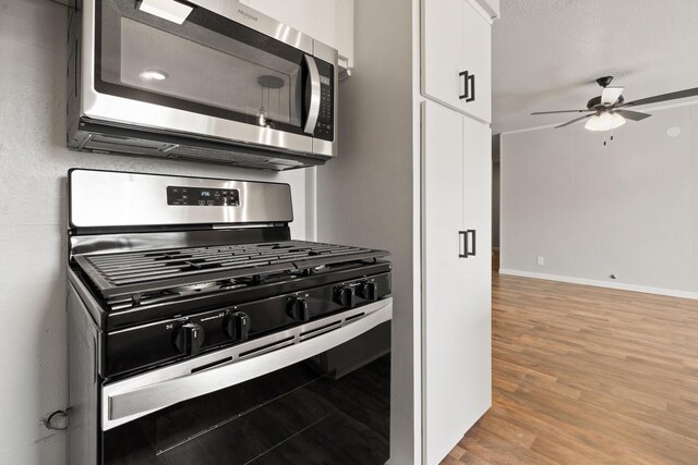 kitchen featuring ceiling fan, white cabinets, a textured ceiling, stainless steel appliances, and light wood-type flooring