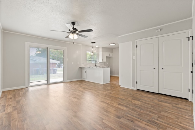 unfurnished living room with dark wood-type flooring, ceiling fan, sink, and a textured ceiling