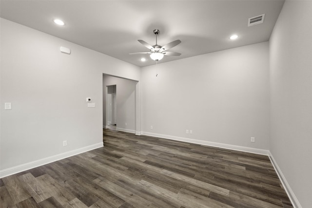 empty room with baseboards, dark wood-type flooring, visible vents, and a ceiling fan