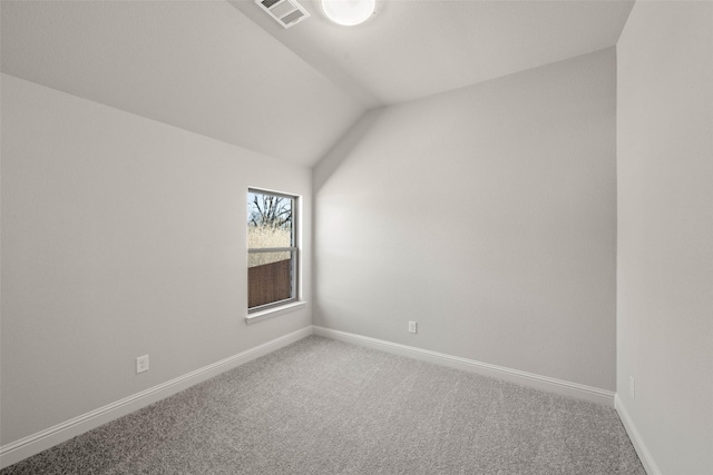 carpeted empty room featuring visible vents, vaulted ceiling, and baseboards