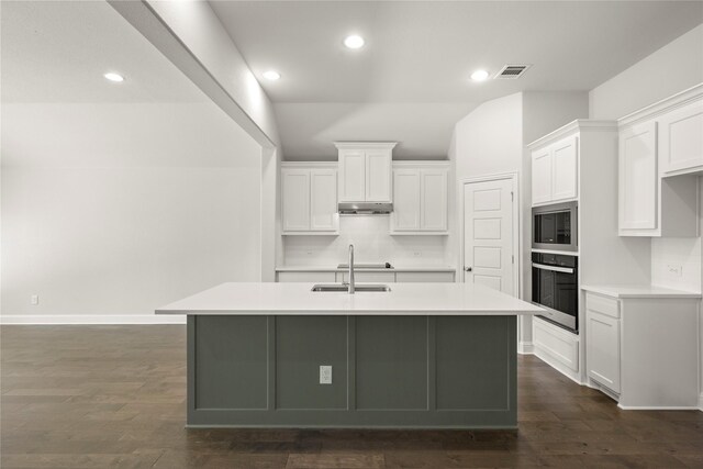 kitchen featuring dark wood-style flooring, stainless steel appliances, visible vents, white cabinets, and a sink