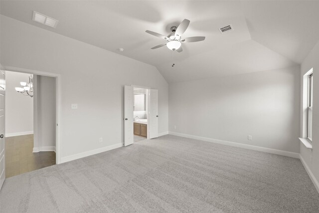 unfurnished bedroom with a walk in closet, visible vents, vaulted ceiling, and baseboards