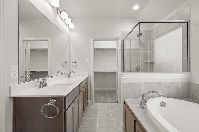 bathroom with a stall shower, a walk in closet, a sink, and tile patterned floors