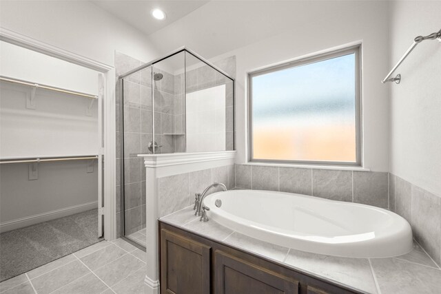 full bath featuring tile patterned flooring, a walk in closet, a sink, and tiled shower