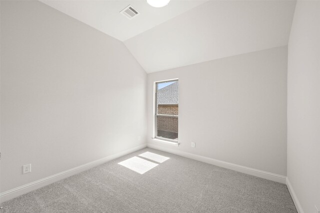 empty room with lofted ceiling, carpet floors, visible vents, and baseboards