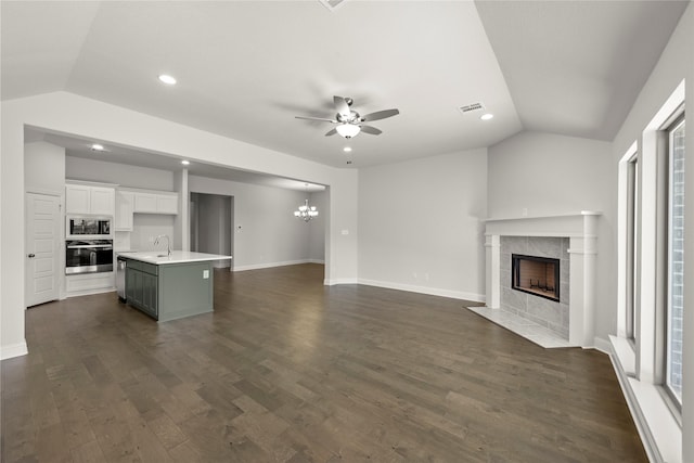 unfurnished living room with lofted ceiling, a fireplace, visible vents, and dark wood-type flooring