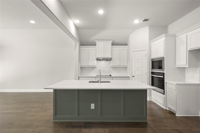 kitchen with visible vents, oven, a kitchen island with sink, built in microwave, and under cabinet range hood