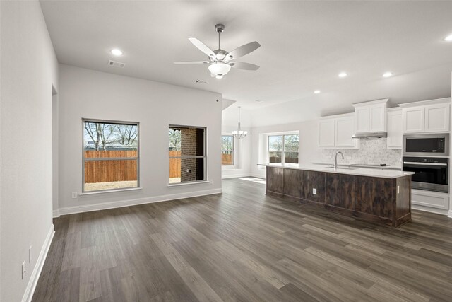 kitchen featuring a sink, open floor plan, appliances with stainless steel finishes, white cabinets, and decorative backsplash