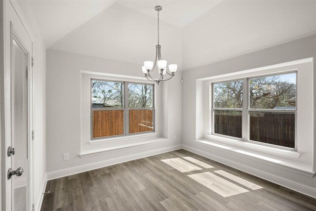 unfurnished dining area featuring a healthy amount of sunlight, wood finished floors, and vaulted ceiling