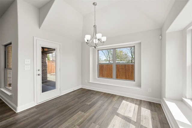 unfurnished dining area with a notable chandelier, baseboards, dark wood-type flooring, and a healthy amount of sunlight