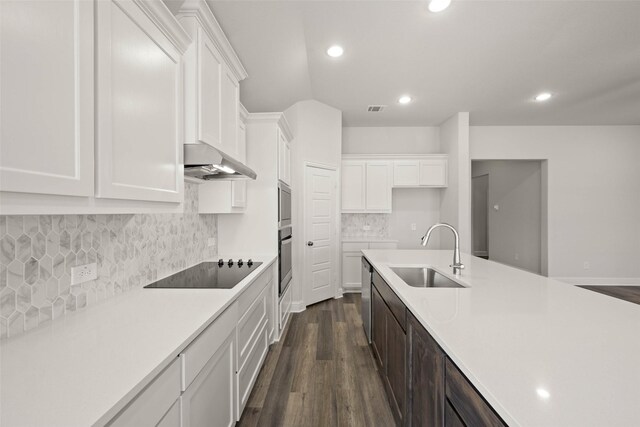 kitchen featuring a sink, under cabinet range hood, white cabinetry, light countertops, and black electric cooktop